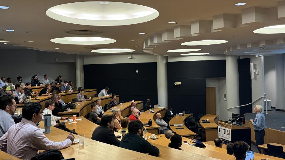 Andrew Dugenske, a principal research engineer at GTMI and symposium organizer, delivering a talk at the symposium&#039;s tenth annual gathering.